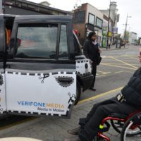 Male wheelchair user about to get into the back door of a black cab