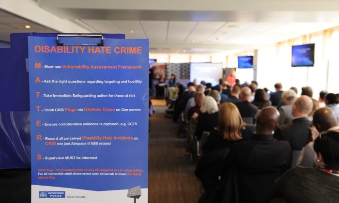 Conference room filled with people, with poster in the foreground reading "Disability Hate Crime MATTERS"