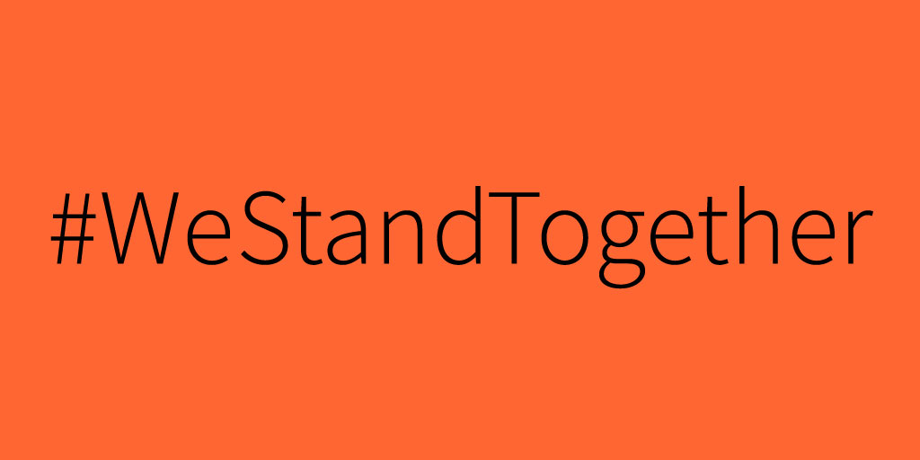 Black text on an orange background reading #WeStandTogether