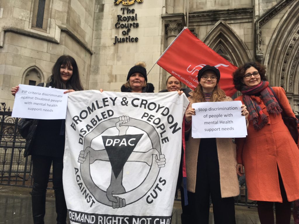Five protestors outside the Royal Courts of Justice with a Bromley and Croydon DPAC banner